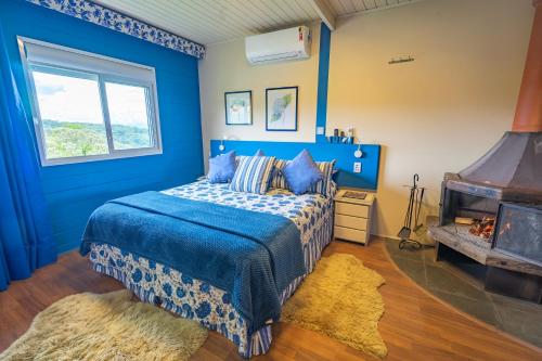 a blue bedroom with a bed and a fireplace at Pousada Alto Da Boa Vista in Campos do Jordão