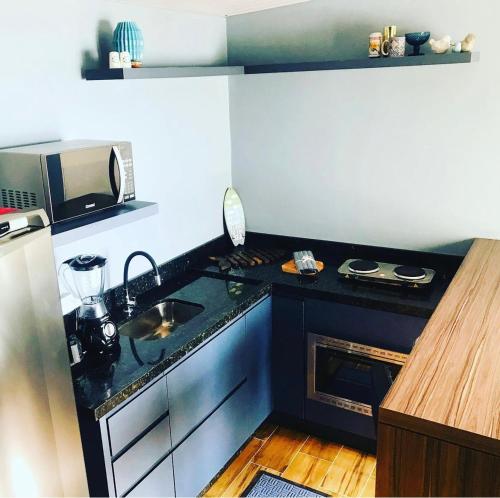Una cocina con encimera negra y fregadero. en Cabana Solitude - Concha, en Florianópolis