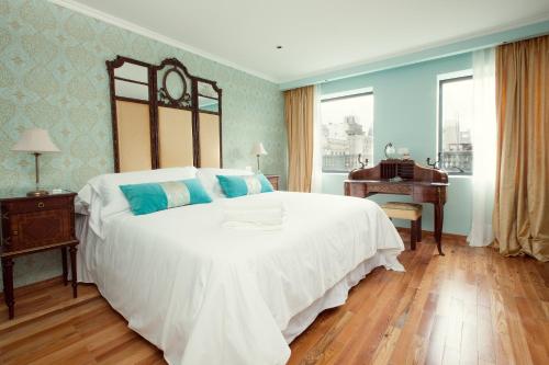 a bedroom with a large white bed and a piano at Alma Histórica Boutique Hotel in Montevideo