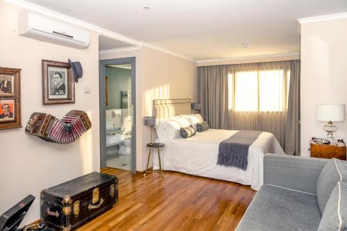 a bedroom with a bed and a living room with a couch at Alma Histórica Boutique Hotel in Montevideo