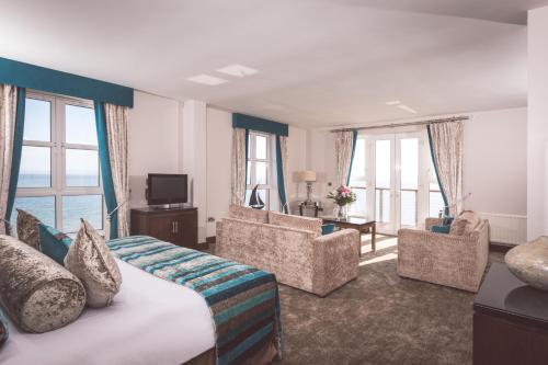 a hotel room with a bed and chairs and windows at Redcastle Hotel in Moville
