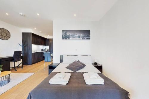 a bedroom with a large bed with two towels on it at Superb Studio in Greenwich with balcony & roof top in London