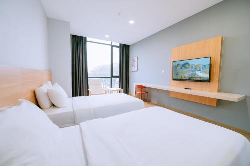 a hotel room with two beds and a tv at Chill Suites Langkawi in Kuah