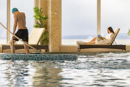 a man and a woman sitting in chairs next to a swimming pool at Redcastle Hotel in Moville