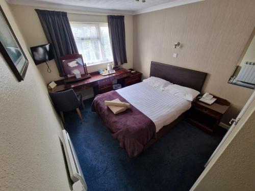a hotel room with a bed and a desk at Grange Lodge Hotel in Saint Peter Port