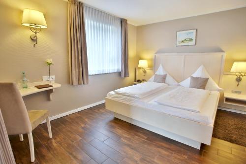 a bedroom with a large white bed and a desk at Anker's Hörn - Hotel & Restaurant auf der Hallig Langeness in Langeneß