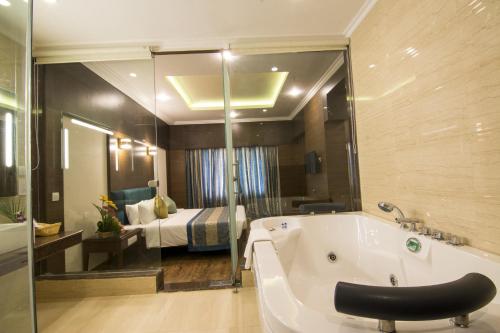a bathroom with a tub and a bedroom with a bed at Shenbaga Hotel And Convention Centre in Pondicherry