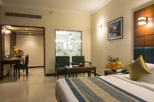 a hotel room with a bed and a table and chairs at Shenbaga Hotel And Convention Centre in Puducherry