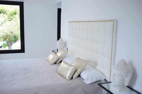 a bedroom with a white bed with pillows at Balinese Villa near the beach outdoor jacuzzi in Cala Llonga