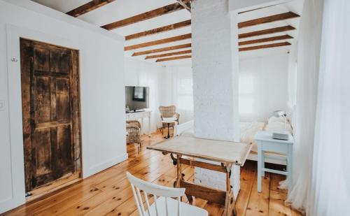 een witte kamer met een houten tafel en stoelen bij An authentic, rustic luxurious little single family home in Old Town. All yours. in Marblehead