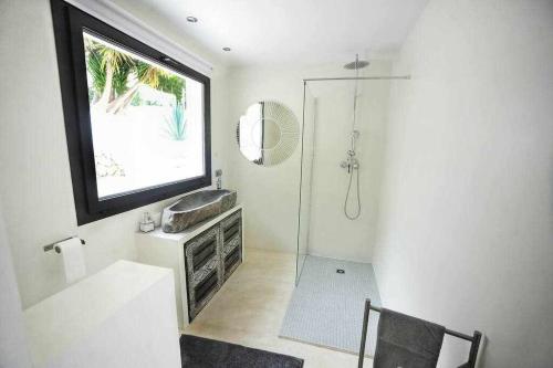 ein Bad mit einer Dusche, einem Waschbecken und einem Fenster in der Unterkunft Balinese Villa near the beach outdoor jacuzzi in Cala Llonga