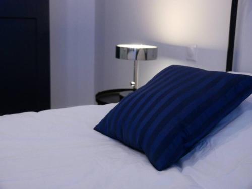 a blue pillow sitting on top of a white bed at Clos de la Providence, gîte, piscine et Spa 3 chambres in Nolay