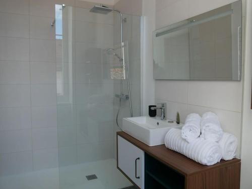 a bathroom with a sink and a shower with towels at Clos de la Providence, gîte, piscine et Spa 3 chambres in Nolay