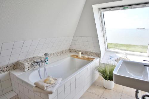 a white bathroom with a tub and a sink at Anker's Hörn - Hotel & Restaurant auf der Hallig Langeness in Langeneß