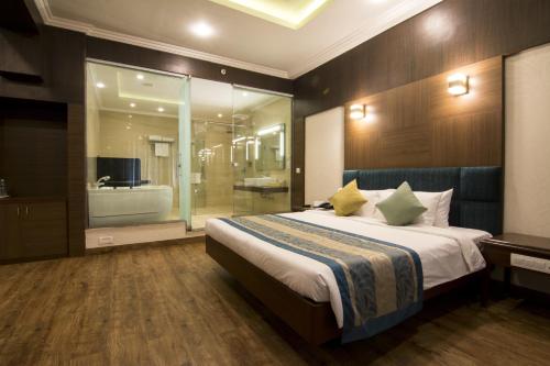 a bedroom with a large bed and a bathroom at Shenbaga Hotel And Convention Centre in Puducherry