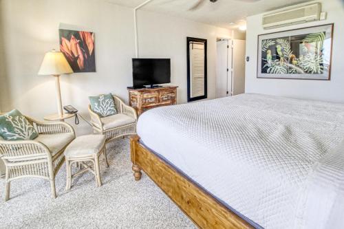 a bedroom with a bed and two chairs and a television at Hanalei Bay Resort 4204 in Princeville