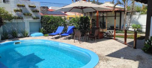 a swimming pool with a table and chairs and an umbrella at Casa nos Ingleses com piscina e jacuzzi in Florianópolis