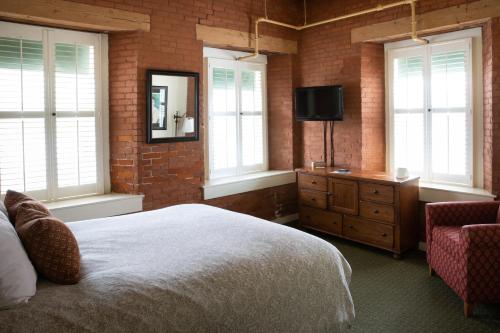 a bedroom with a bed and a tv and windows at The Common Man Inn & Restaurant in Claremont
