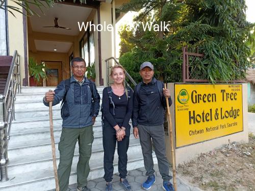 un gruppo di tre persone in piedi accanto a un cartello di Green Tree a Chitwan