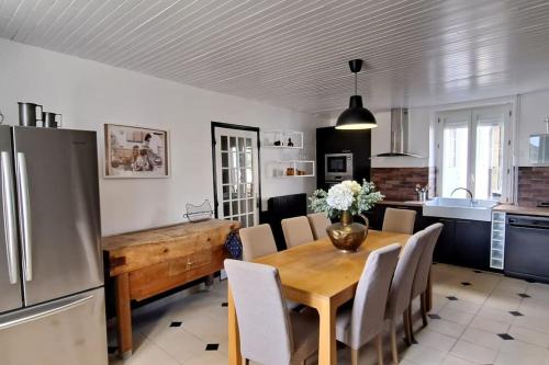 uma cozinha e sala de jantar com uma mesa e um frigorífico em La Cousinade em Cauroy-lès-Hermonville