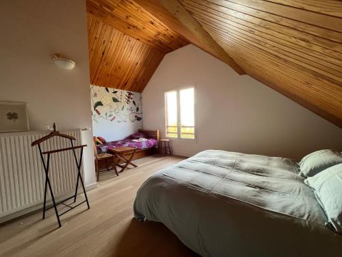 a bedroom with a large bed and a wooden ceiling at Eco-Logis Mad'in Belledonne in Theys