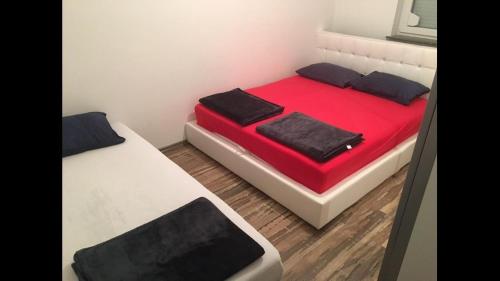 1 Schlafzimmer mit 2 Betten mit roter Bettwäsche und schwarzen Kissen in der Unterkunft Apartment Balicevac Ilidza in Sarajevo