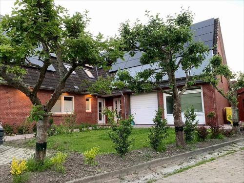 Kleine Auszeit Pellworm في بيلفورن: منزل من الطوب وامامه اشجار