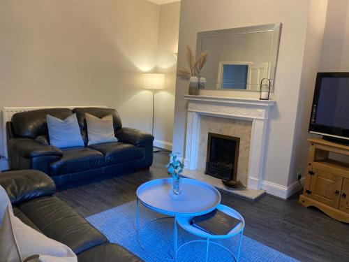 ein Wohnzimmer mit einem Sofa, einem Tisch und einem Kamin in der Unterkunft Alexander Apartments Jesmond in Newcastle upon Tyne