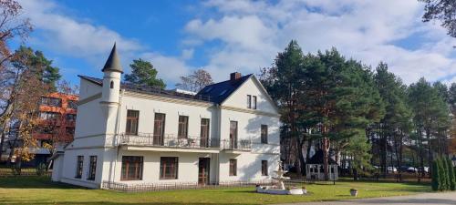 a white house with a turret on top of it at BURMISTRO NAMAS in Druskininkai