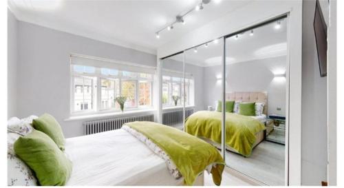 a white bedroom with two beds with green sheets at 9 Brentwood Lodge in London