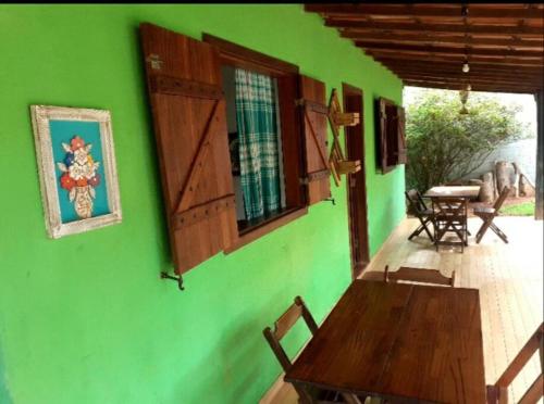 a green wall with a wooden table on a patio at Casa das Violetas - Serra do Cipó in Serra do Cipo