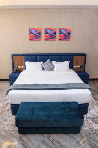 a bedroom with a large bed with two paintings on the wall at South Gate Hotel Apartment in Addis Ababa