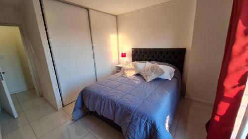 um quarto com uma cama com um edredão e almofadas azuis em Confort Río Cuarto I em Río Cuarto