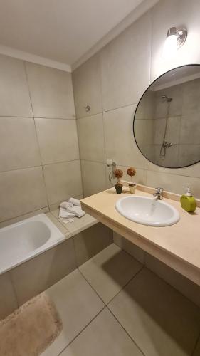 een badkamer met een wastafel, een bad en een spiegel bij Confort Río Cuarto I in Río Cuarto