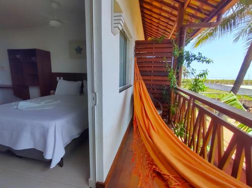a hammock in a room with a bed on a balcony at NaPraia Brasil Pousada in São Miguel do Gostoso
