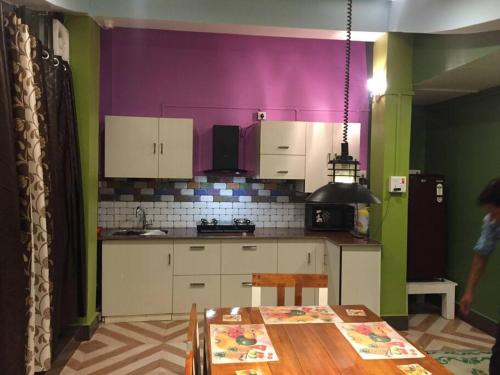a kitchen with a table and a purple wall at LEISHA Duplex in Imphal