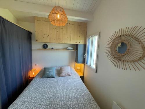 une petite chambre avec un lit et un miroir dans l'établissement Charmante petite maison avec jardin plage des vieilles, à La Croix