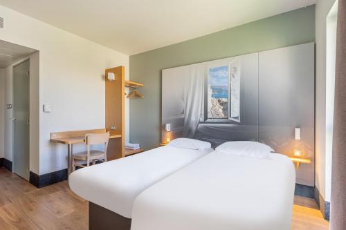 a bedroom with a large white bed and a desk at B&B HOTEL Marseille Euromed in Marseille