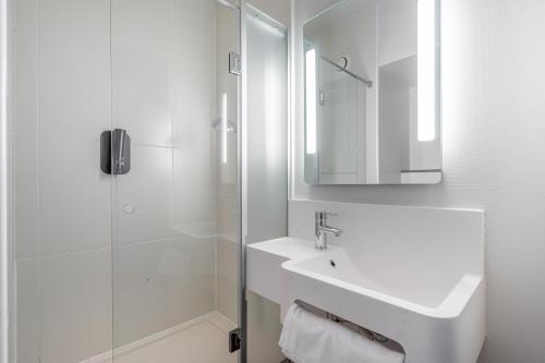 La salle de bains blanche est pourvue d'un lavabo et d'une douche. dans l'établissement B&B HOTEL Marseille Euromed, à Marseille
