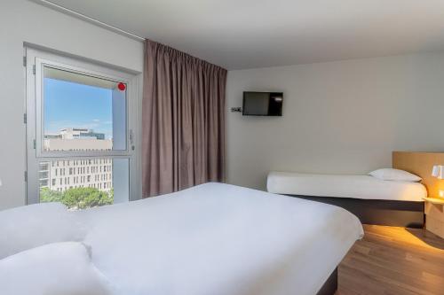 a hotel room with two beds and a window at B&B HOTEL Marseille Euromed in Marseille