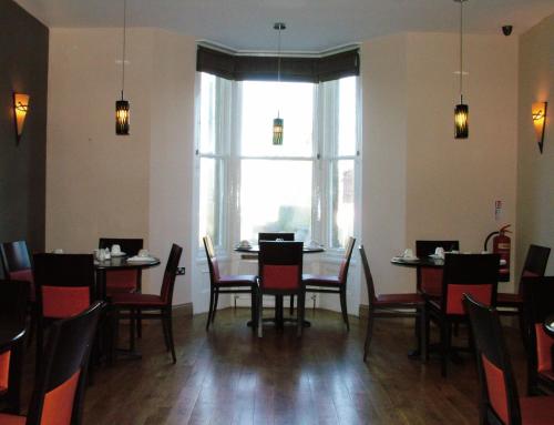 a dining room with tables and chairs and a large window at The Abbey Lodge Hotel in Bradford