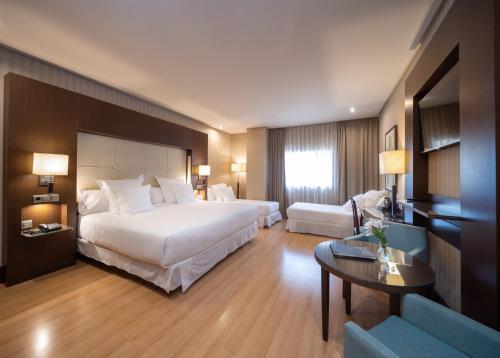 グラナダにあるバルセロ グラナダ コングレスの大きなベッドとテーブルが備わるホテルルームです。