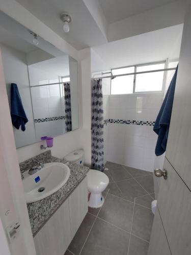 y baño con lavabo, aseo y espejo. en Apartamento Aqualina Orange Quinto Piso Vista a Montañas, en Girardot