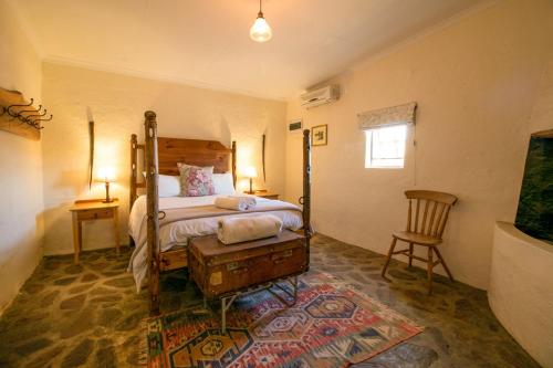 a bedroom with a bed and a table and a chair at Wild Olive Cottage in Graaff-Reinet