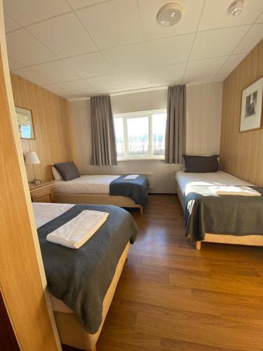 a hotel room with three beds and a window at Hotel Skaftafell in Skaftafell