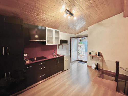 a kitchen with black cabinets and a wooden floor at Green Man Gerês Mountain House in Campo do Gerês