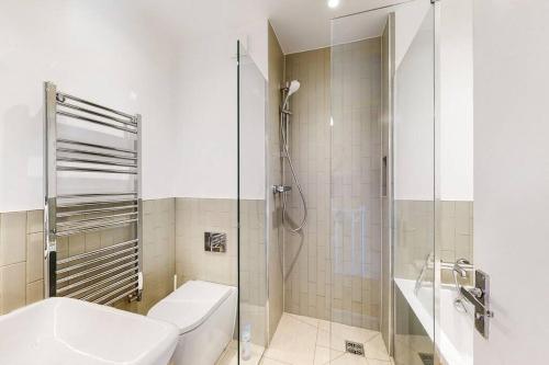 a bathroom with a toilet and a glass shower at Charming 2-bedroom maisonette with private garden in London