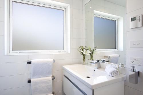 baño blanco con lavabo y ventana en Casa Vista Apartment by Amazing Accom, en Queenstown