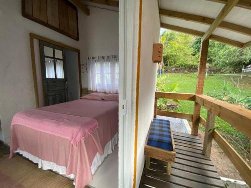 a bedroom with a bed and a porch with a window at Casa Praia da Gamboa - Cabanas da Candoca, Vista para o mar in Garopaba