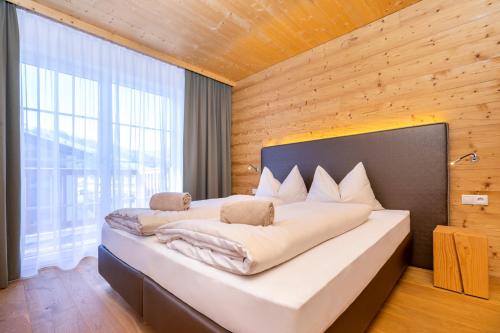 a bedroom with a large bed with a wooden wall at Ferienanlage Central in Flachau